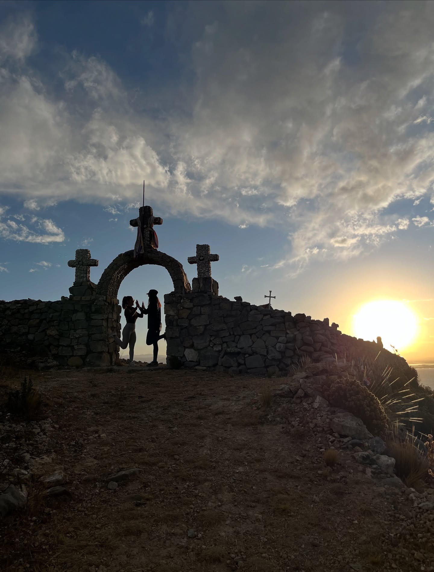 Visitantes bajo un arco de piedra al atardecer